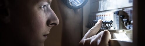 Homeowner using flashlight to find tripped breaker