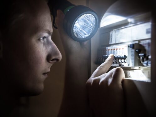 Homeowner using flashlight to find tripped breaker